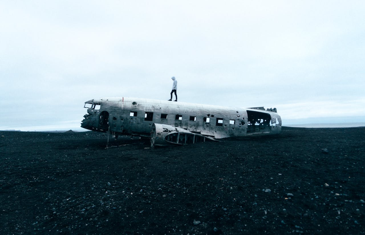 Eerie scene of an abandoned plane wreck on Icelandic beach with a person standing on top.